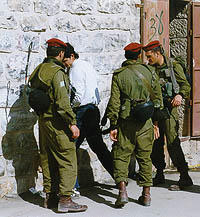 Photo: Israeli soldiers searching a Palestinian youth in Hebron